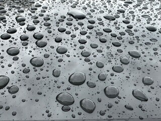 Big rain drops on the metal surface with sky reflection. After rain background