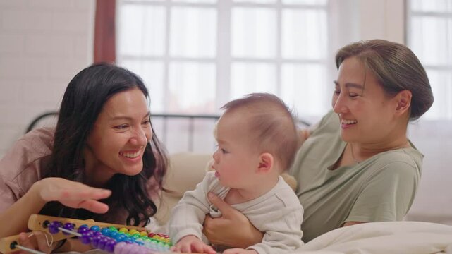 Asian lesbian couple lovingly caring for and raising their baby boy at home.