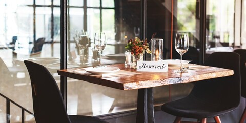 Cozy restaurant table with 'Reserved' sign, elegant glassware, and soft lighting. Intimate dining setup, perfect for special occasions. Reserved table ambiance. Table reserved at bistro restaurant.