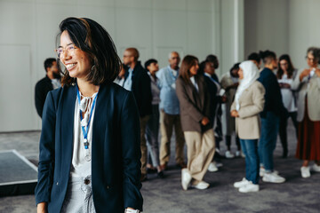 Diverse crowd at a business conference with a smiling professional woman in the foreground