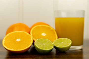 A healthy smoothie in glass with oranges and lime.Glass of orange juice, oranges