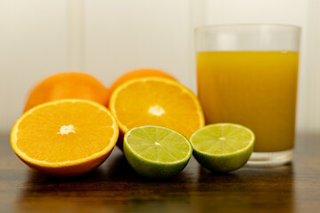 A healthy smoothie in glass with oranges and lime.Glass of orange juice, oranges