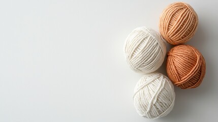 Four yarn balls in soft hues of white and orange, arranged neatly on a light background, ideal for knitting or crafting projects.