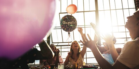 Group celebrating with balloons and laughter. Joyful atmosphere with diverse friends. Festive balloons, cheerful people, and a bright setting create a lively scene. Happy friends at birthday party.