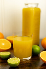 A healthy smoothie in glass with oranges and lime.Glass of orange juice, oranges