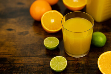 Cut oranges and limes on the table. A glass of orange juice. Citrus