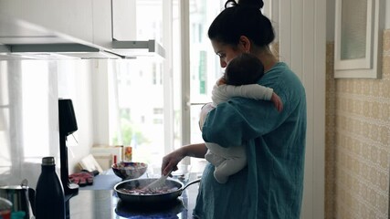 Mother holding baby while cooking in a bright kitchen, multitasking and balancing parenting with daily chores, showcasing nurturing and care in a modern home environment with natural light