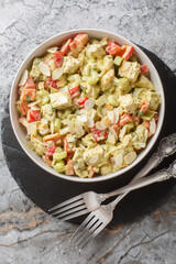 Homemade Genovese Pesto Chicken Salad with celery, onion, pepper and almond flakes close up on the table. Vertical top view from above