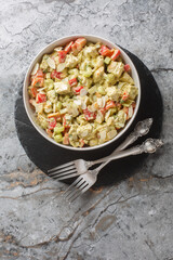 Fresh homemade salad with chicken, seasonal vegetables and almonds close-up in a plate on the table. Vertical top view from above