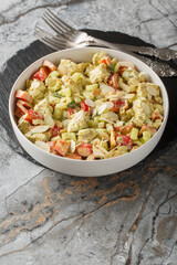 Homemade Genovese Pesto Chicken Salad with celery, onion, pepper and almond flakes close up on the table. Vertical