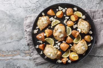 Greek cuisine Skinless chicken thighs with feta, lemon, garlic and potatoes close-up in a frying pan on the table. Horizontal top view from above