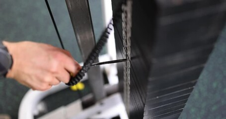 A dedicated person adjusts weights on a gym machine, showing their commitment to fitness and daily exercise