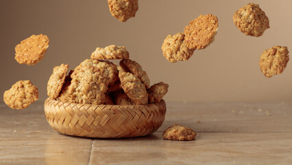 Oatmeal cookies in motion on a beige background.