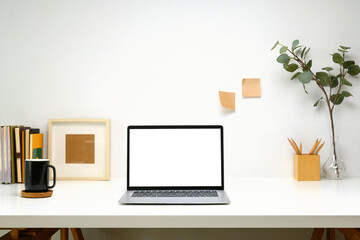 Laptop with blank screen, planner and a white coffee mug on white table, minimalist and modern...