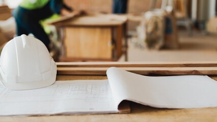 Construction site with blueprints and hard hat. Blueprints on table, hard hat nearby. Construction tools and blueprints, essential for planning. Construction in a home.