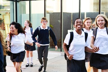 Group of diverse high school students in uniforms. Smiling and walking, high school students are enjoying their day. High school students outdoors. Diverse teenage students in uniforms at school.