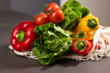 Close up of fresh seasonal vegetables in an eco net shopper bag on grey kitchen table
