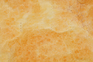A close-up shot of the textured surface of a baked puff pastry showcasing its golden hue and detailed pattern