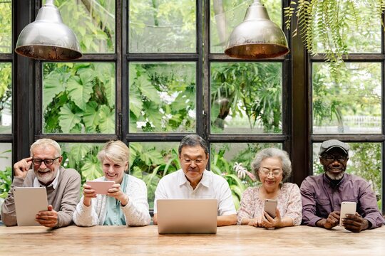 Group of diverse seniors using technology. Elderly men and women with laptops and tablets. Multicultural seniors enjoying tech devices together. Diverse seniors using digital devices.