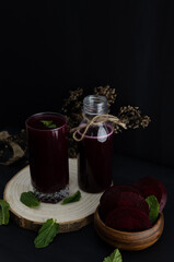 Vertical image of beet smoothie on a wooden log on a dark background, dark red healthy drink with high antioxidant power. Dark food