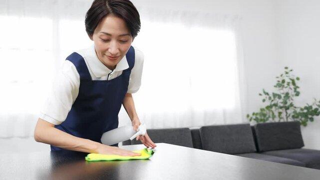 部屋を掃除するエプロンをつけたミドル女性