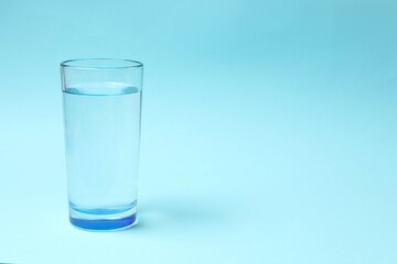 Transparent glass with water on blue background. Drinking clear water in the morning for health