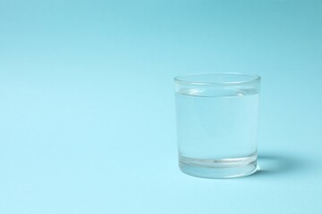 Transparent glass with water on blue background. Drinking clear water in the morning for health
