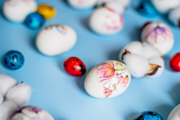 Easter beautiful decorated orthodox religious chicken and quail eggs and lush balls of cotton flowers lie on a blue background