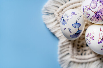 Easter beautiful decorated Orthodox religious chicken eggs with flowers lie on a white napkin macro on a blue background with space for text