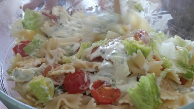 Creamy pasta salad with fresh lettuce, cherry tomatoes, and bowtie pasta in a bowl