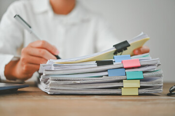 A person is writing on a stack of papers with a pen