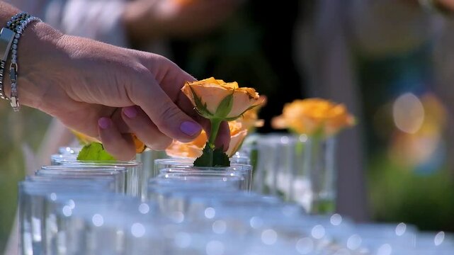 Close up view of a luxury wedding table setting with candles and flowers arrangement in glass vases in a garden.
