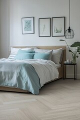 Obraz premium Modern bedroom with light wooden flooring, light teal bedding, and framed artwork.