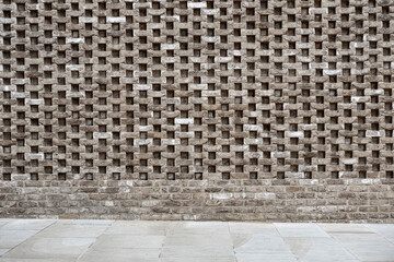 Modern perforated brick wall with geometric pattern and urban design.