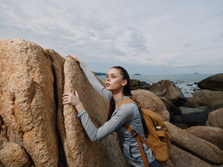 Young woman exploring rocky landscape, wearing sporty outfit and backpack, exuding determination in...