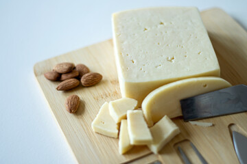 Cheese on a wooden board with almonds and tools for cheese cutting