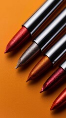 Sparkling Metallic Eye Shadow Crayons Arranged on a Flat Orange Background for Cosmetics Promotion