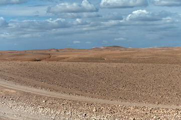 Fototapeta premium Distant mountains and cloudy skies over the Agafay Desert in Morocco during midday