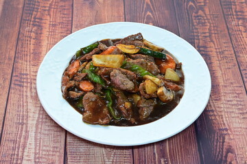 A plate of meat and vegetables with a brown sauce
