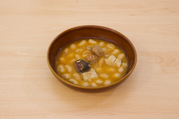 A bowl of soup with beans and meat in it