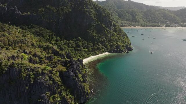 Drone flight over Corong Corong Beach with boats along the shore, offering a scenic view of the beach and Las Cabanas in the distance.
