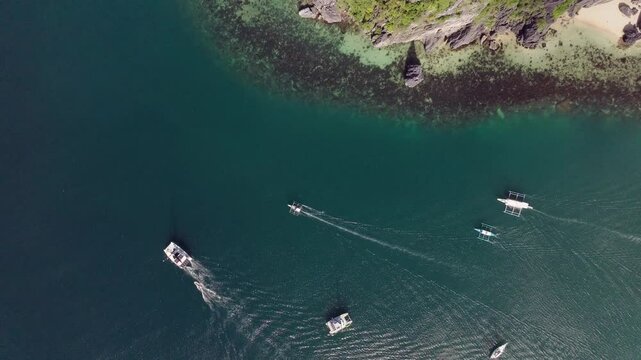 Drone flight over Corong Corong Beach with boats along the shore, offering a scenic view of the beach and Las Cabanas in the distance.

