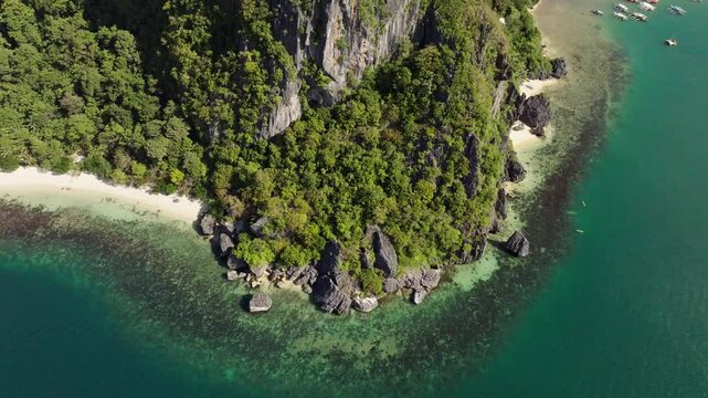 Drone flight over Corong Corong Beach with boats along the shore, offering a scenic view of the beach and Las Cabanas in the distance.
