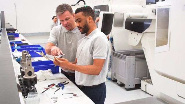 Engineer And Male Apprentice Measuring Components In Hi Tech Engineering Plant