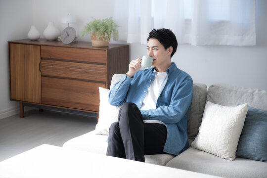 リビングでコーヒーを飲むくつろぐ若い男性