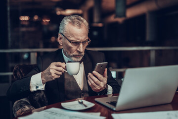 Businessman talking on Phone and nibbles glasses