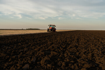 Obraz premium Tractor on the field during sunset.