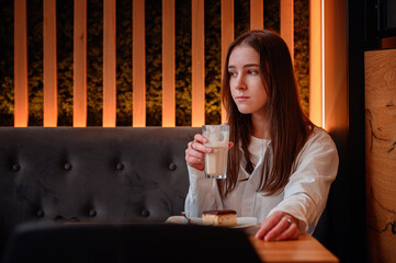 Young Woman Enjoying a Latte in a Cozy Cafe