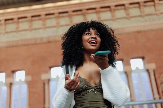 Young woman sending a vocal message on smart phone in train station