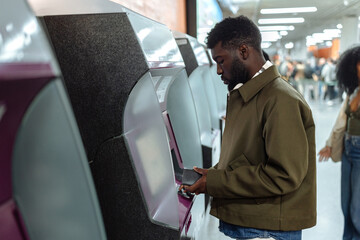 Young man buying subway ticket at automatic ticket machine
